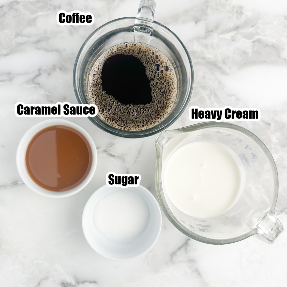 A cup of coffee, bowl of caramel sauce, heavy cream, and sugar. 