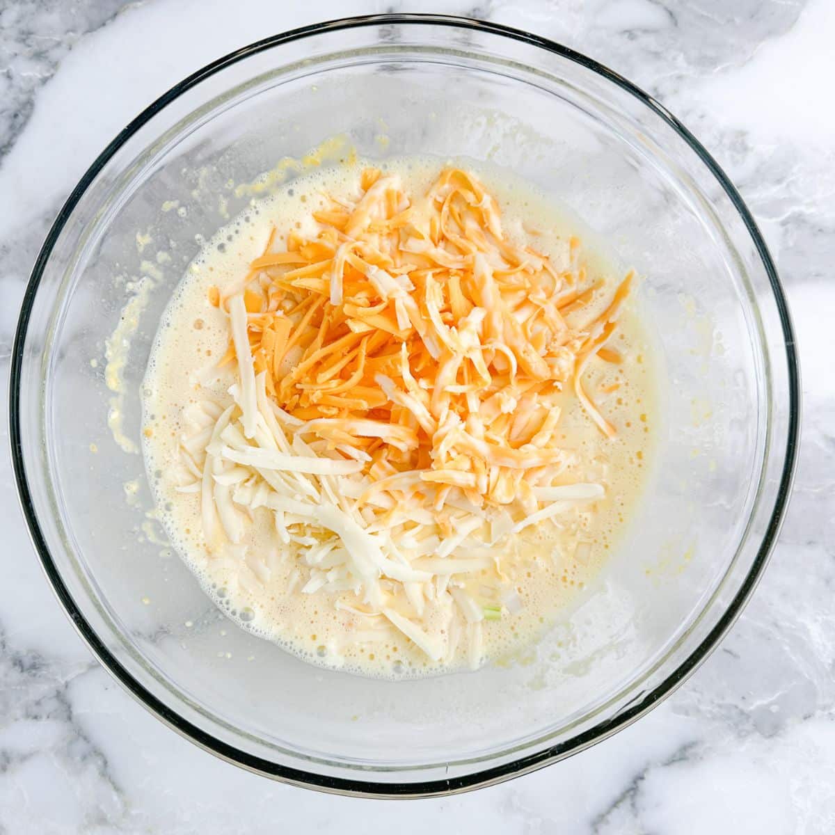 Bowl with beaten egg and shredded cheese. 