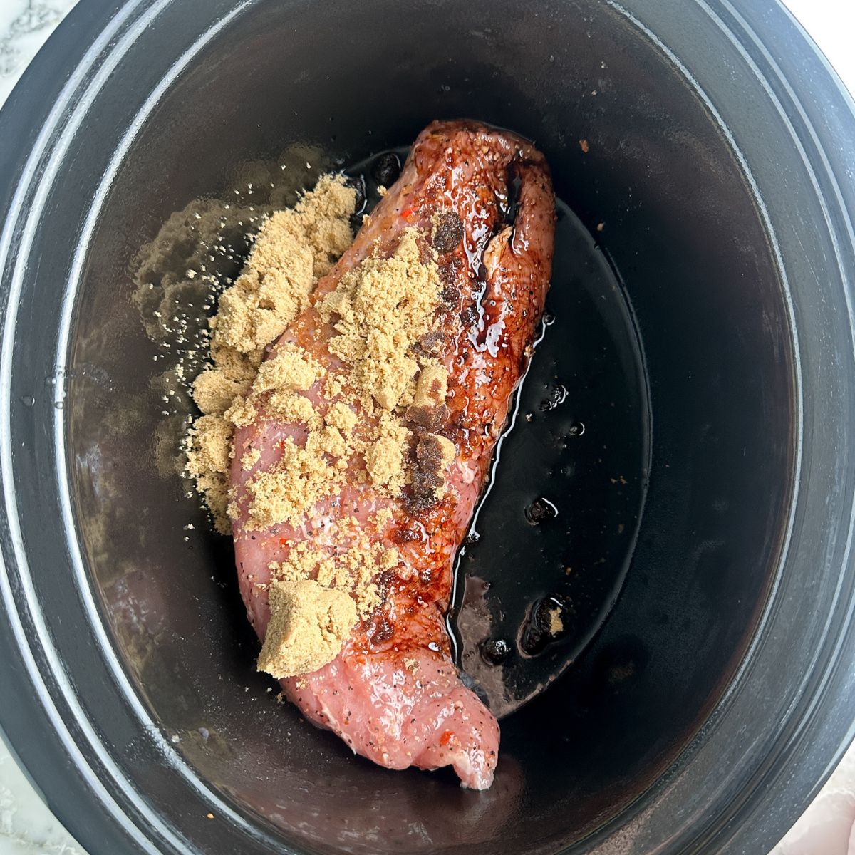 Pork in a slow cooker with brown sugar and soy sauce.