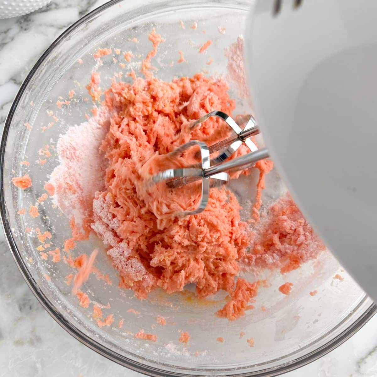 Bowl with strawberry bars batter and a mixer.