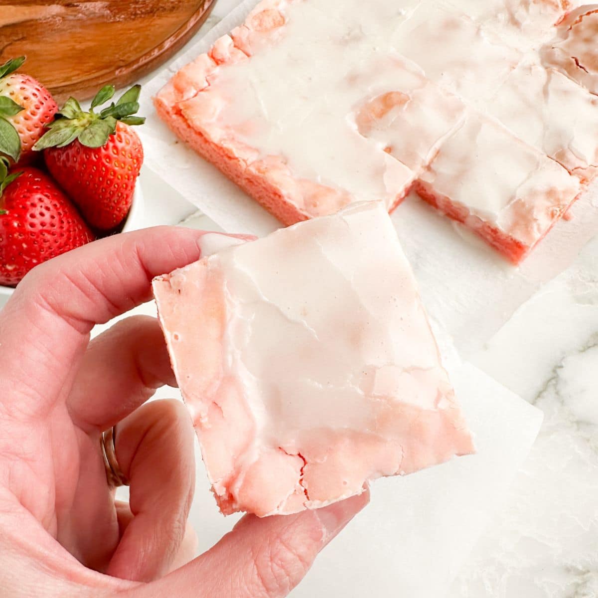 Hand holding a strawberry brownie.