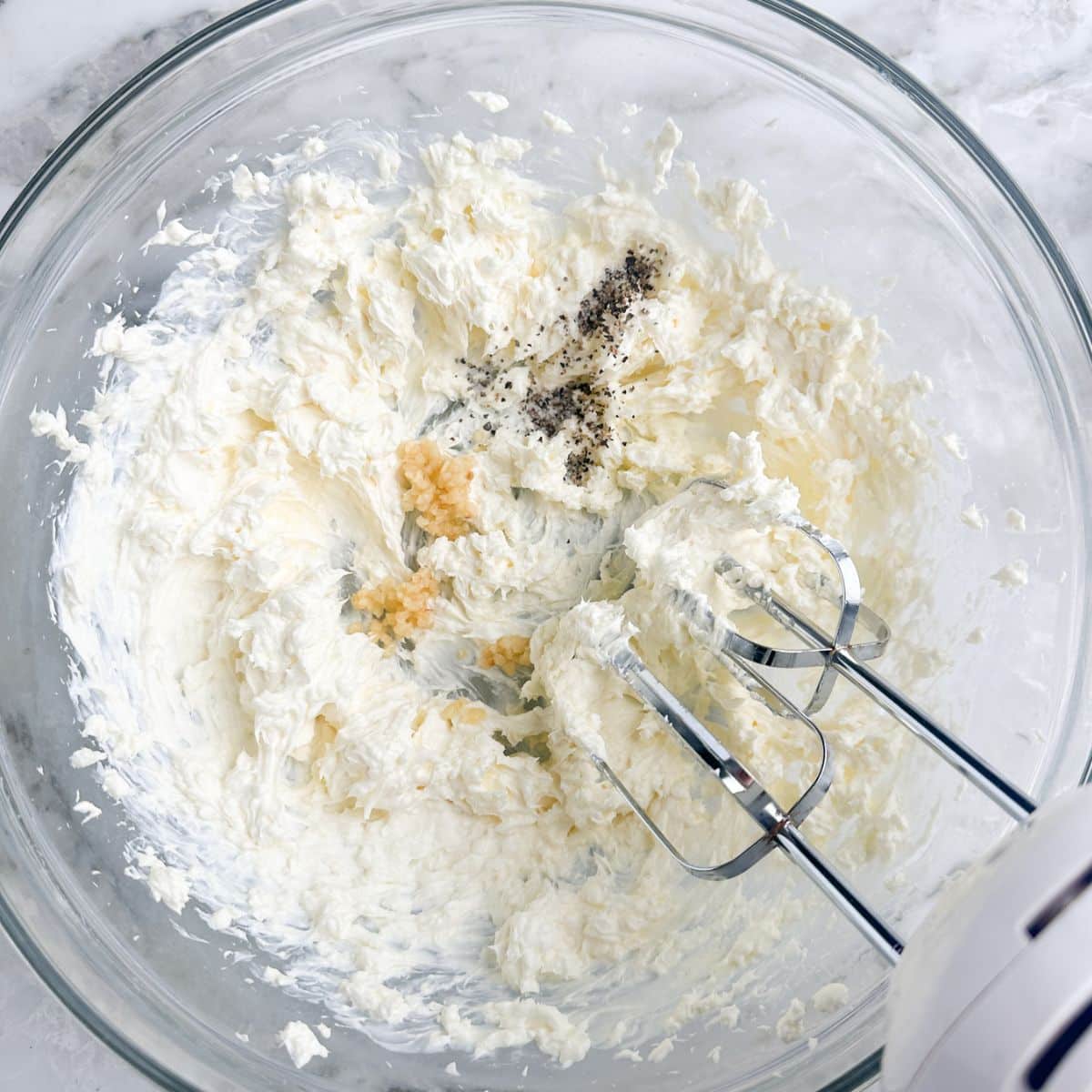 Bowl with whipped cream cheese and mixer.