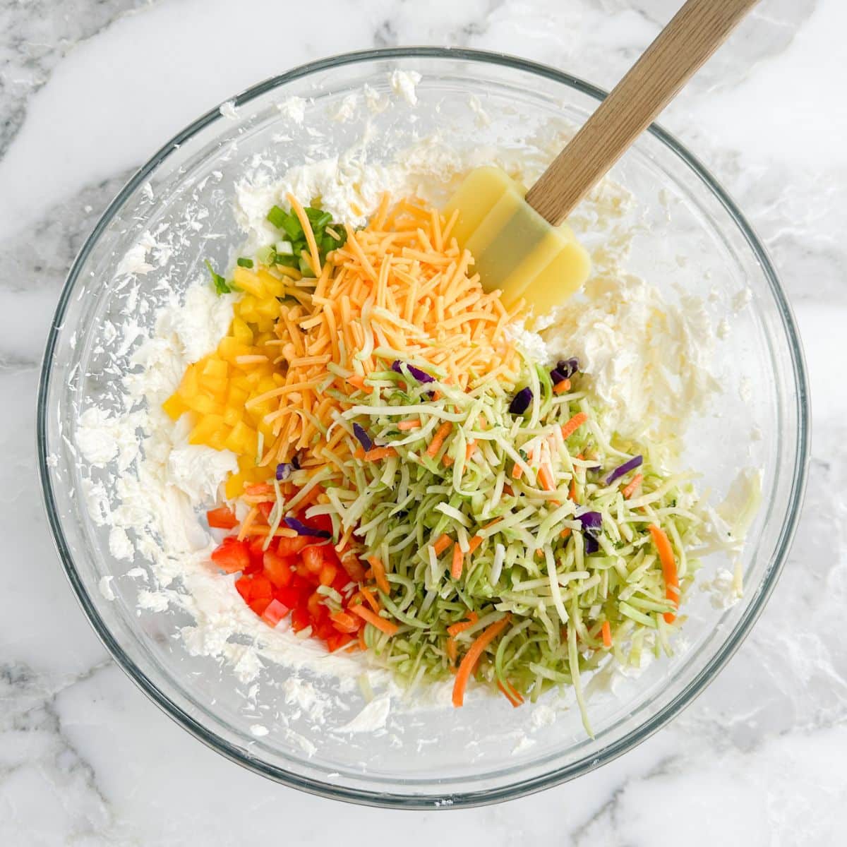 Bowl of cream cheese, chopped vegetables, and shredded cheese.