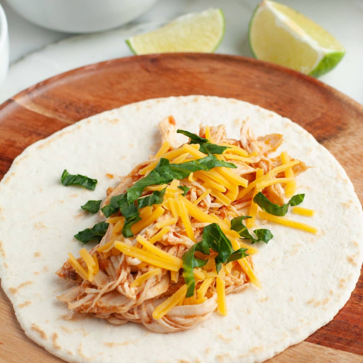 Tortilla with shredded chicken topped with cheese and lettuce. 