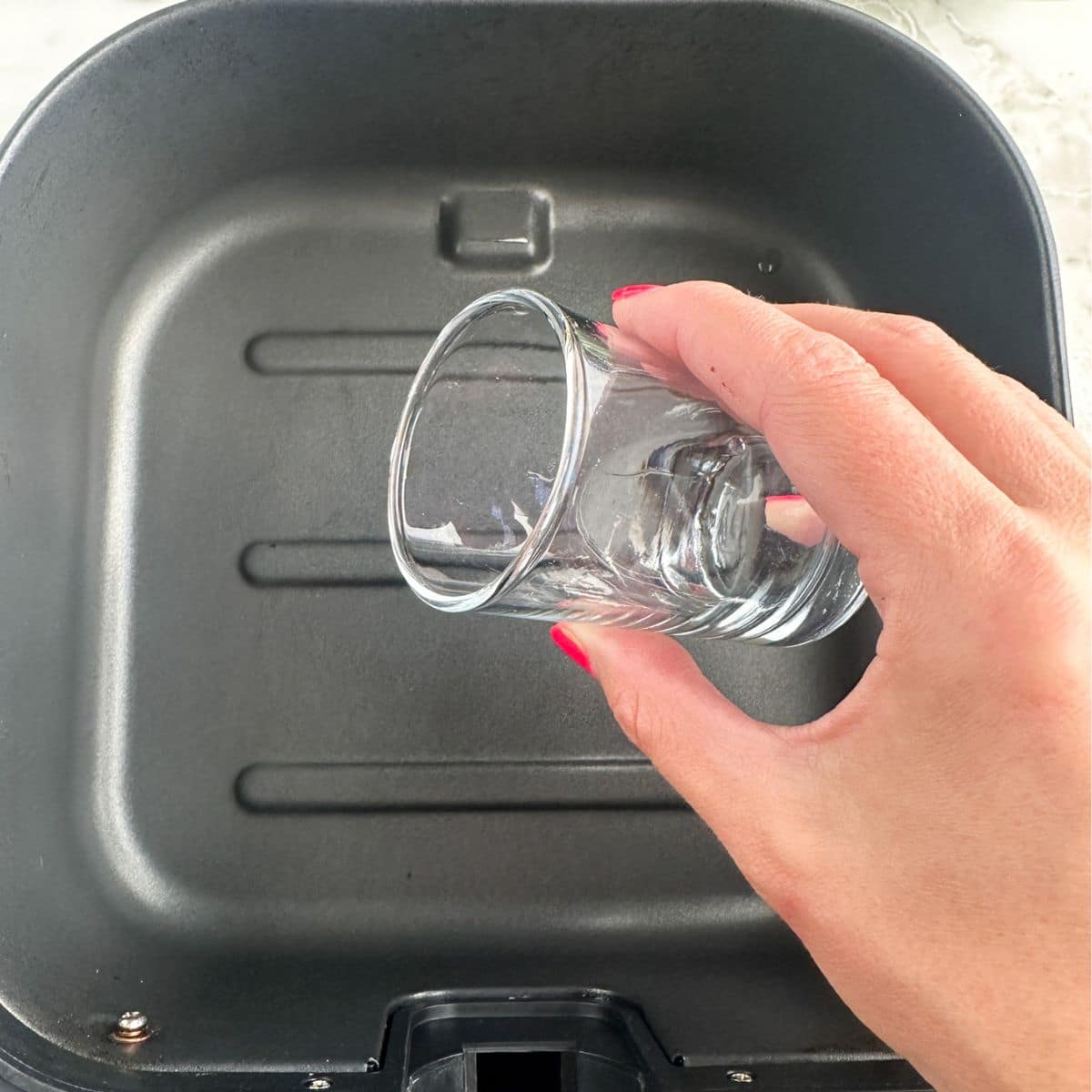 Pouring water into an air fryer basket. 