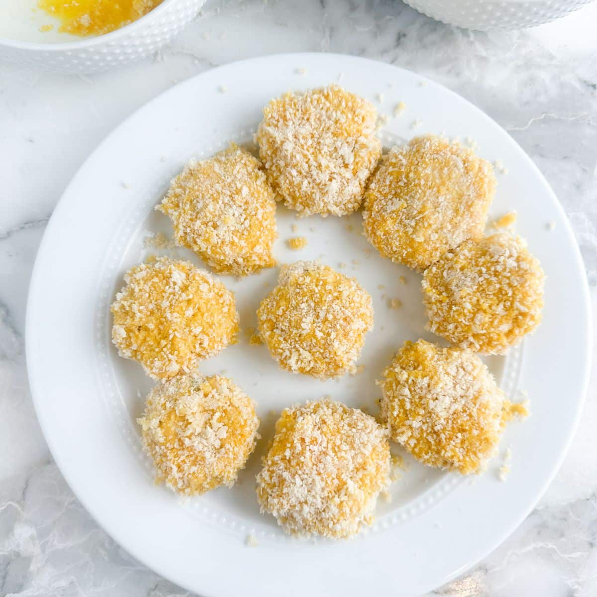 Plate of uncooked chicken croquettes.