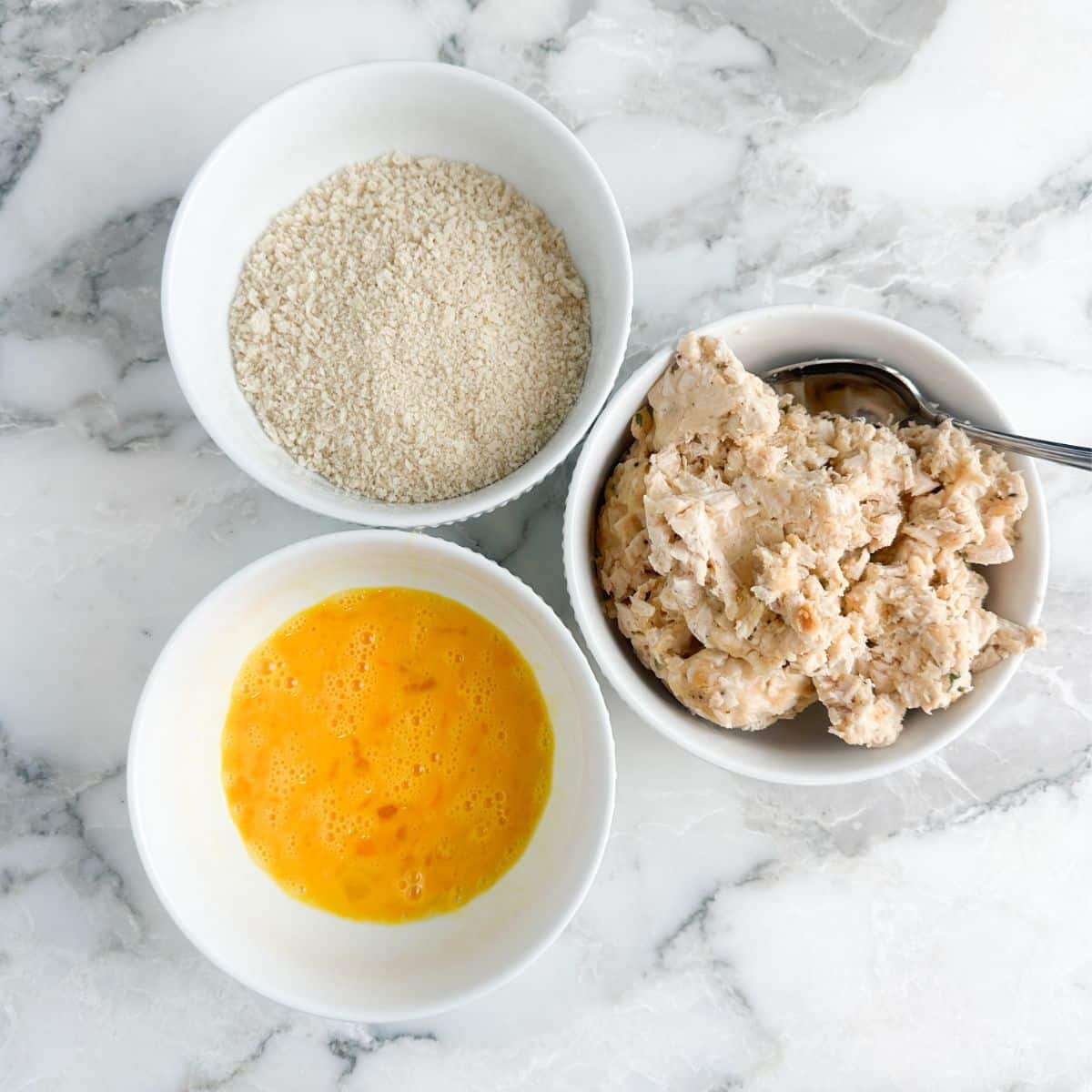 Bowls of whisked eggs, panko crumbs, and chicken croquette mixture. 