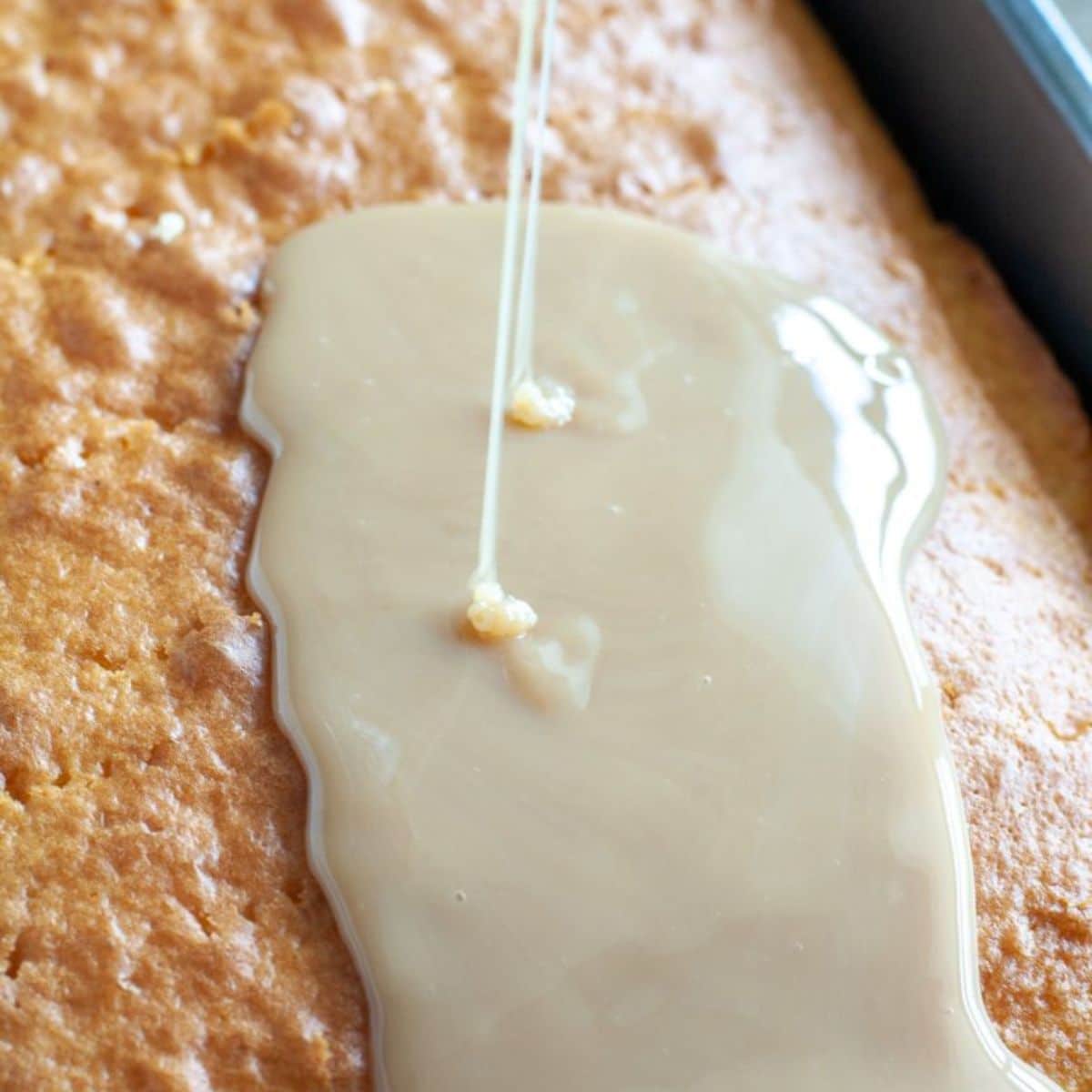 Cake with sweetened condensed milk pouring on top of it. 