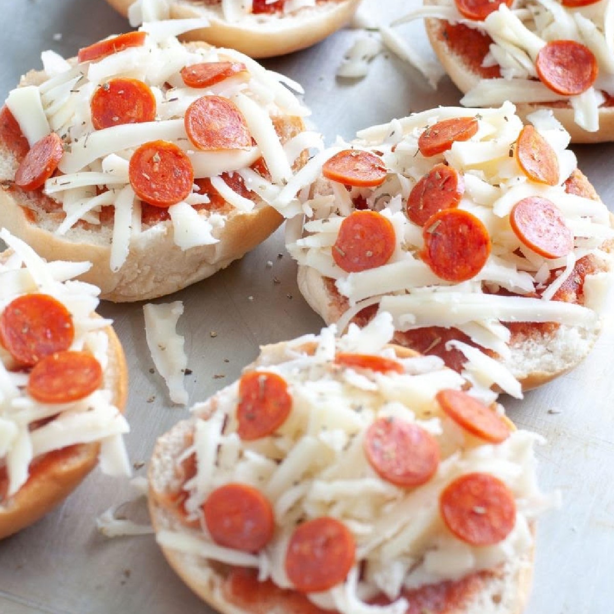 Uncooked pizza bagels on a baking pan.