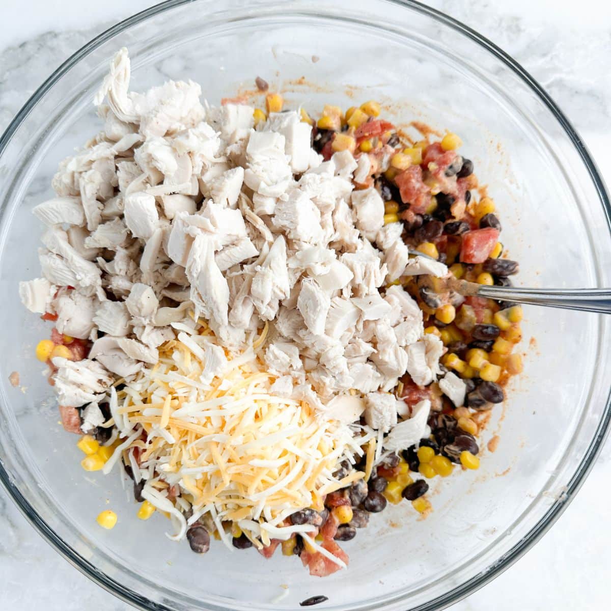 Bowl with bean mixture, diced chicken, and shredded cheese.