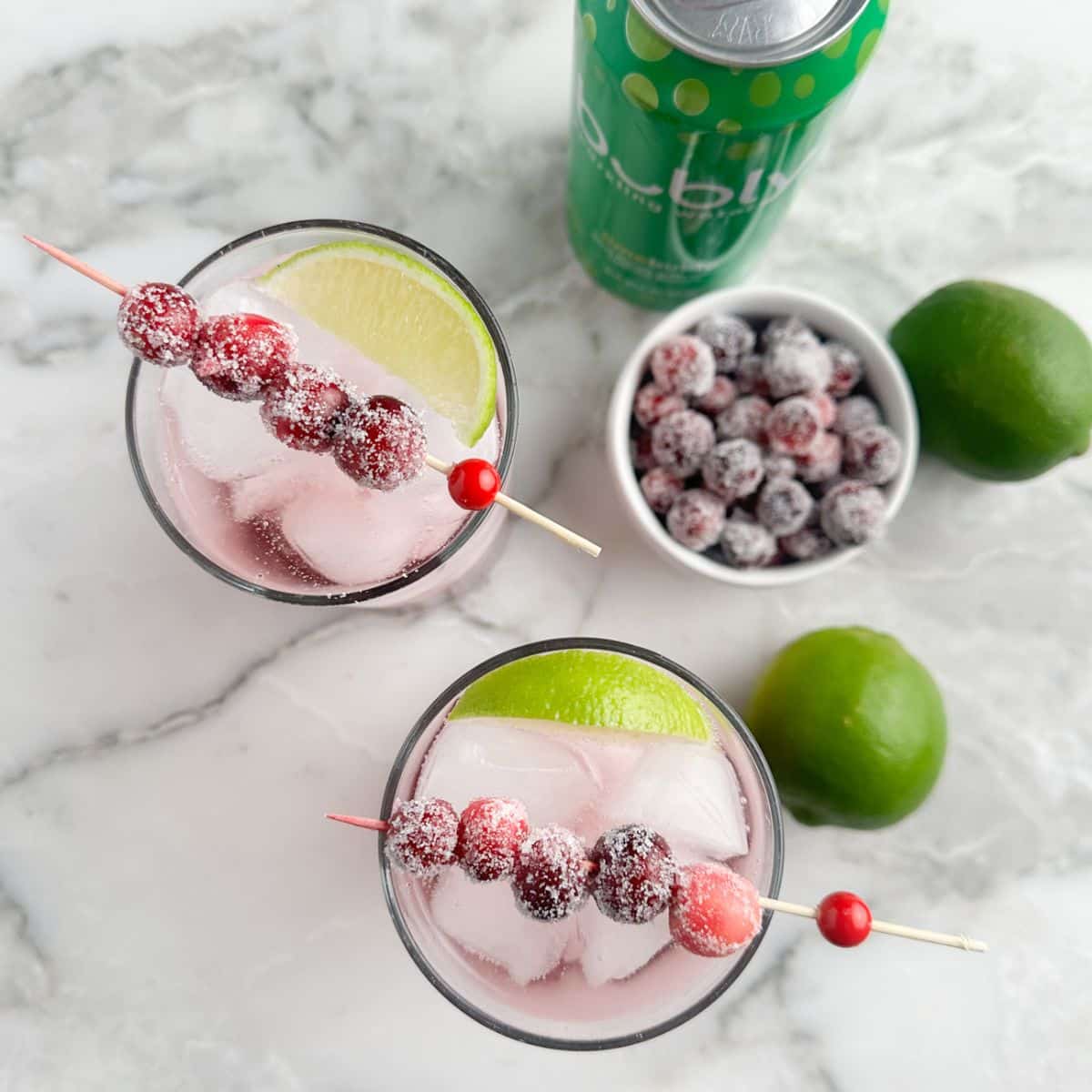 Glasses with cranberry mocktail, limes, and sugared cranberries. 