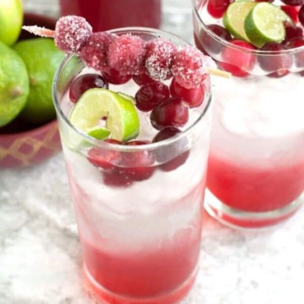 Glass of cranberry mocktail with sugared cranberries and lime.