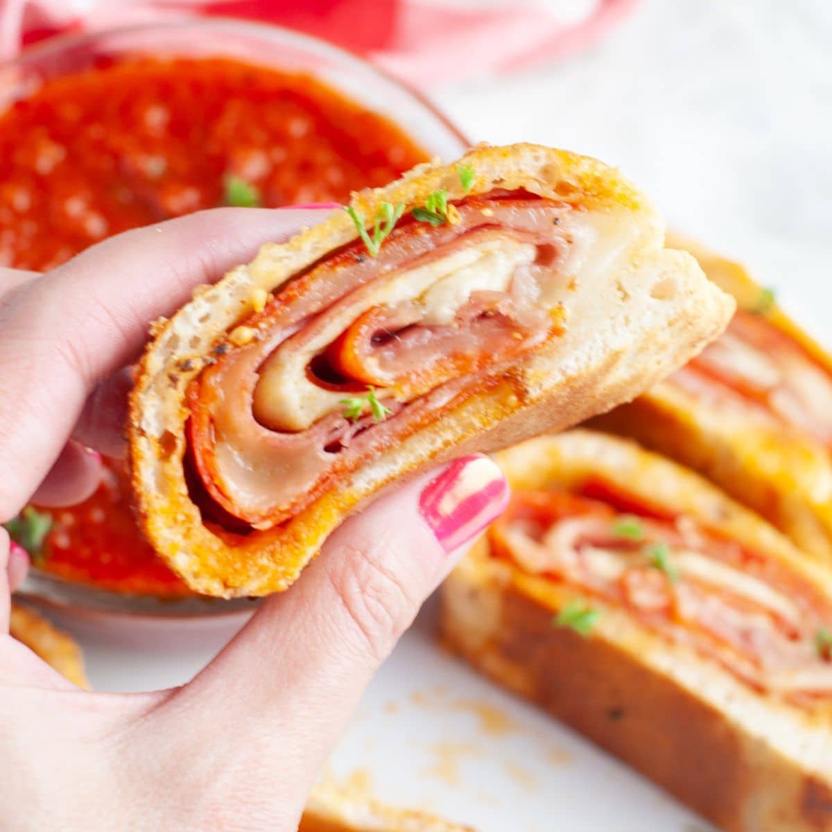 Hand holding a piece of stromboli. 