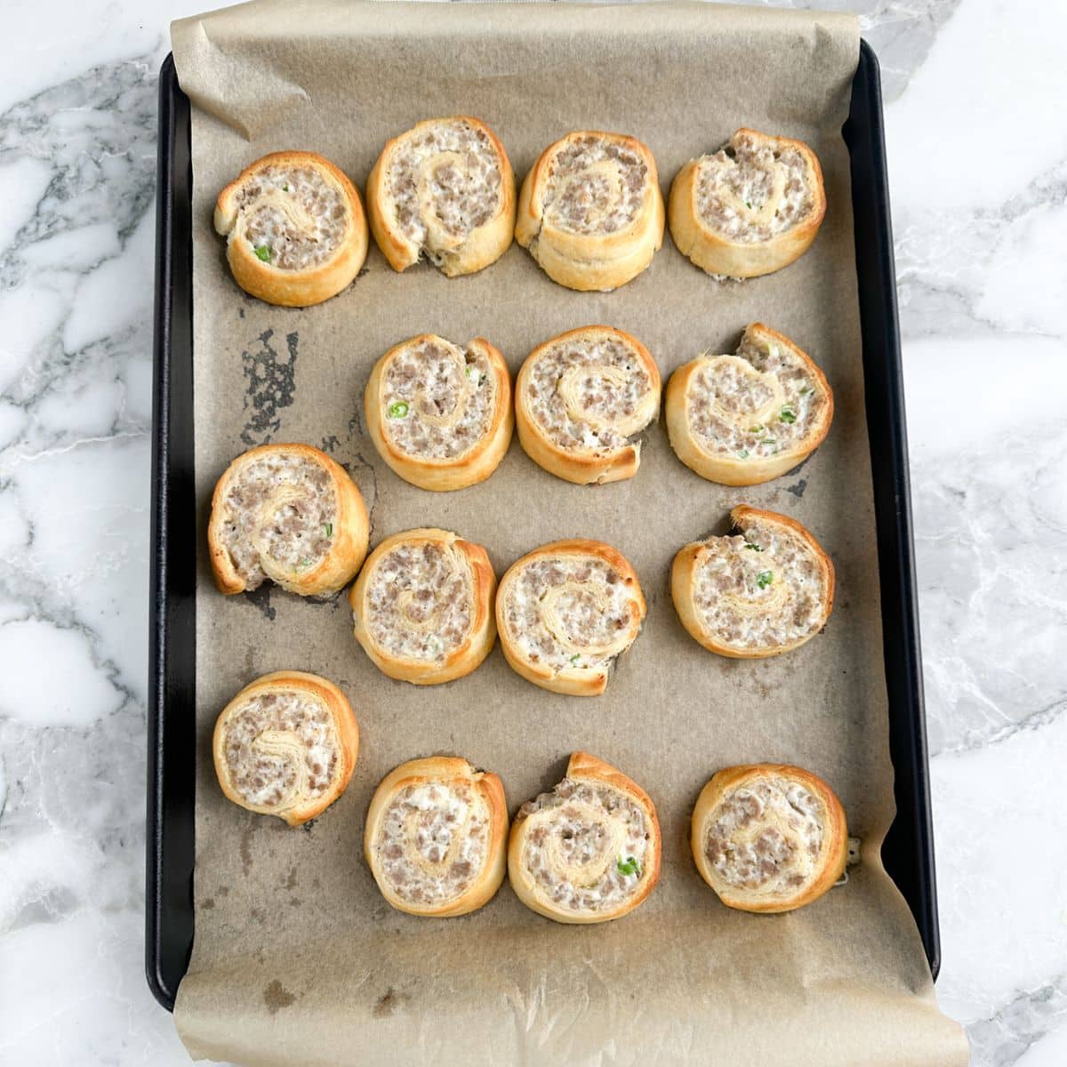 Baking sheet with baked sausage rolls.