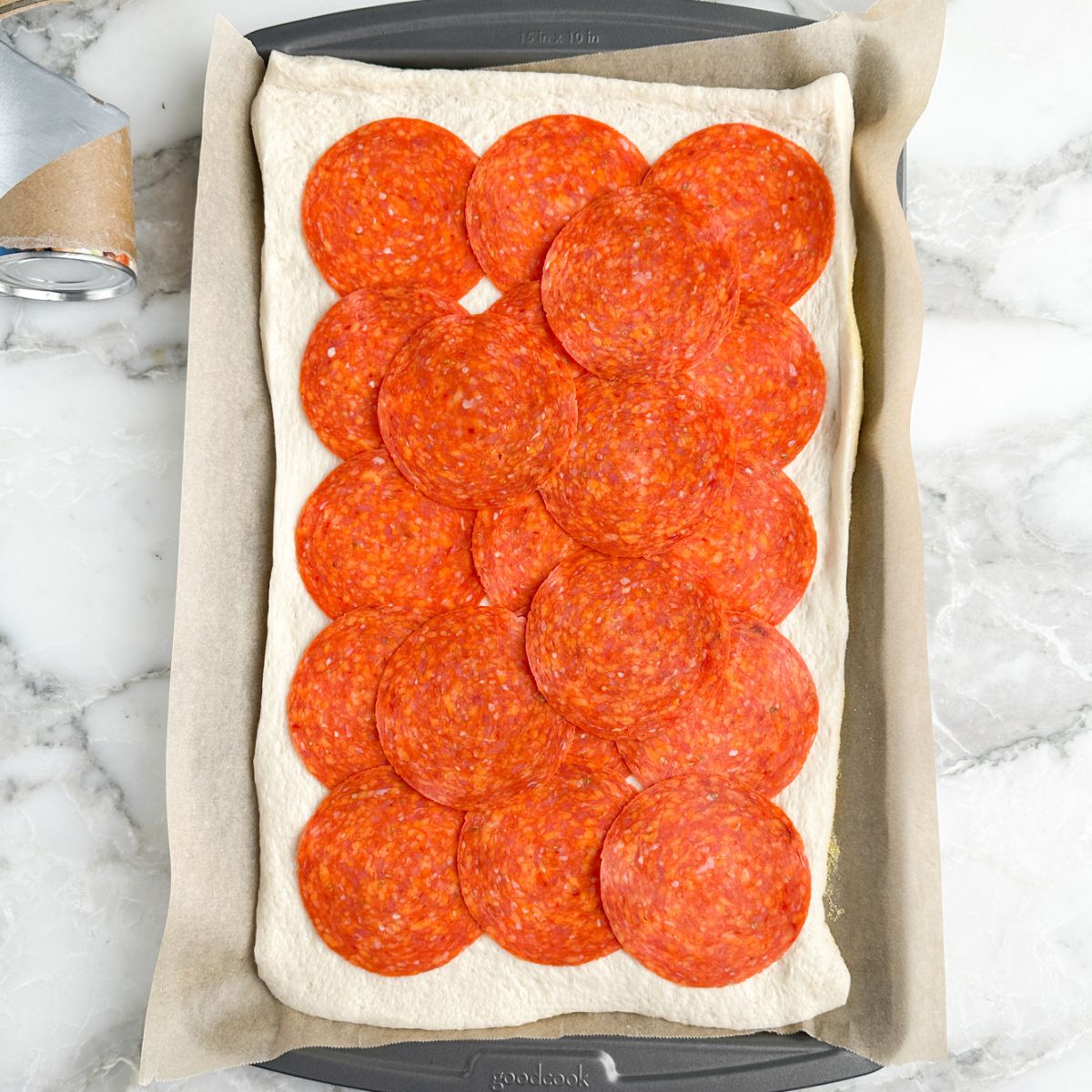 Pizza dough topped with pepperoni. 