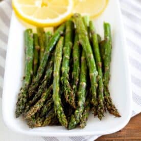 Plate with cooked asparagus and lemon slices.