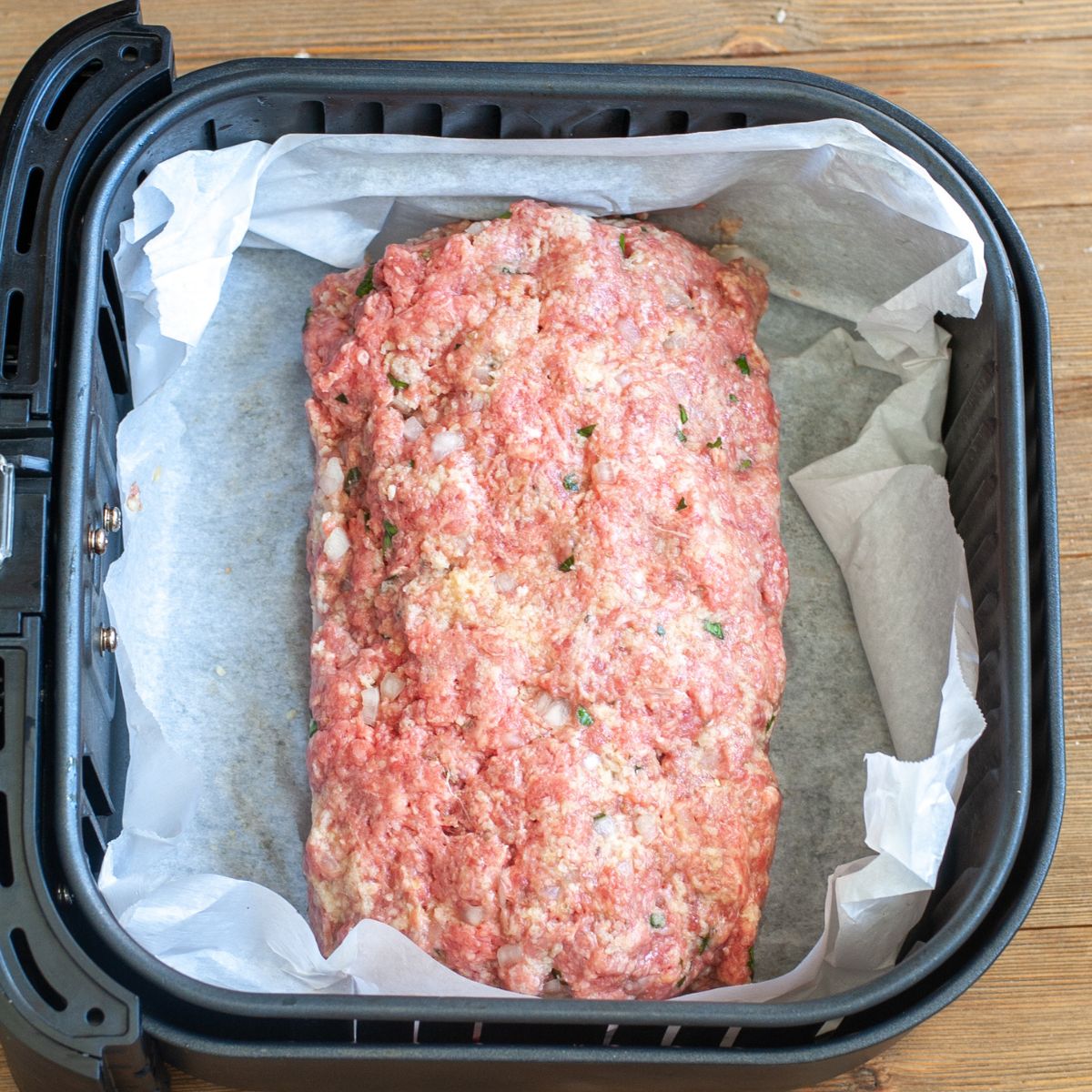 Uncooked meatloaf in air fryer basket.