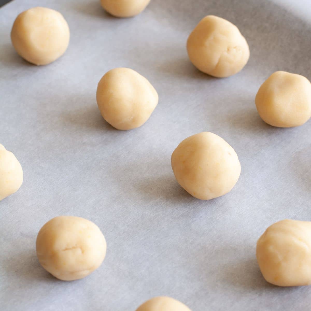 Cookie dough balls on parchment paper. 