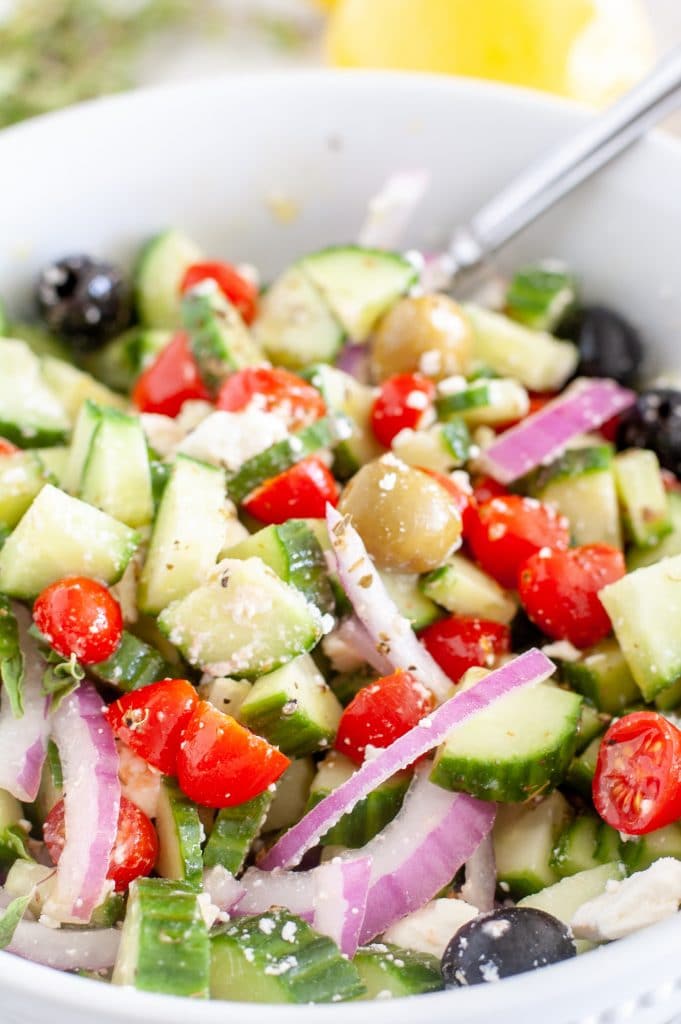 Cucumber tomato salad in a bowl with a fork