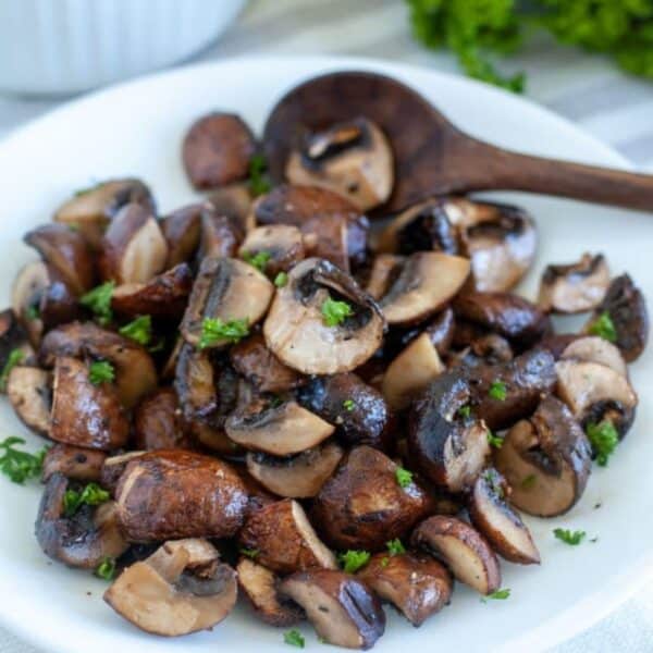 Plate of cooked mushrooms with a wooden spoon.