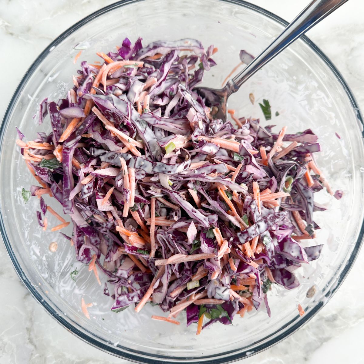 Bowl of red cabbage slaw with a spoon. 