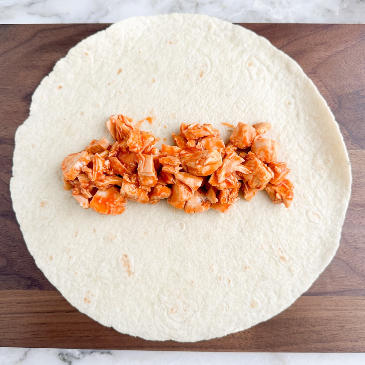 Tortilla with buffalo chicken on top.