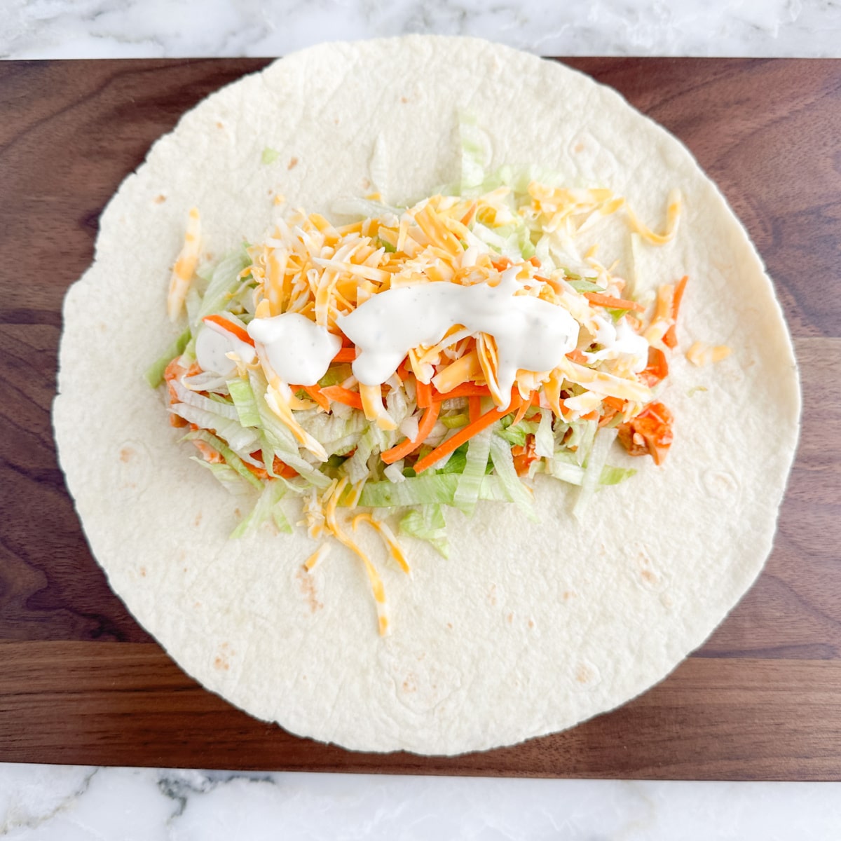 Tortilla with buffalo chicken, lettuce, cheese, and ranch.