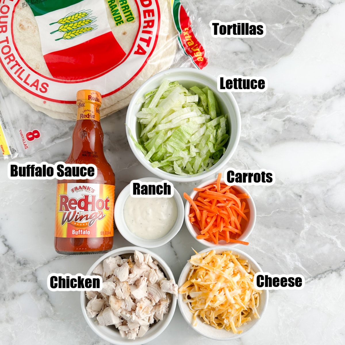 Tortillas, bowl of lettuce, carrots, cheese, ranch, chicken, and buffalo sauce.