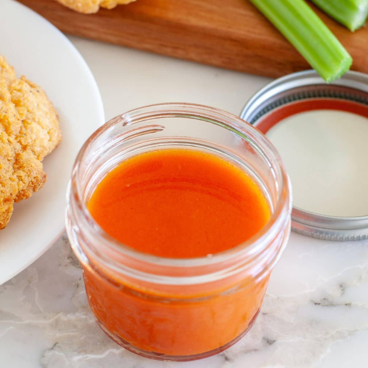 Bowl of buffalo sauce with celery stalk. 