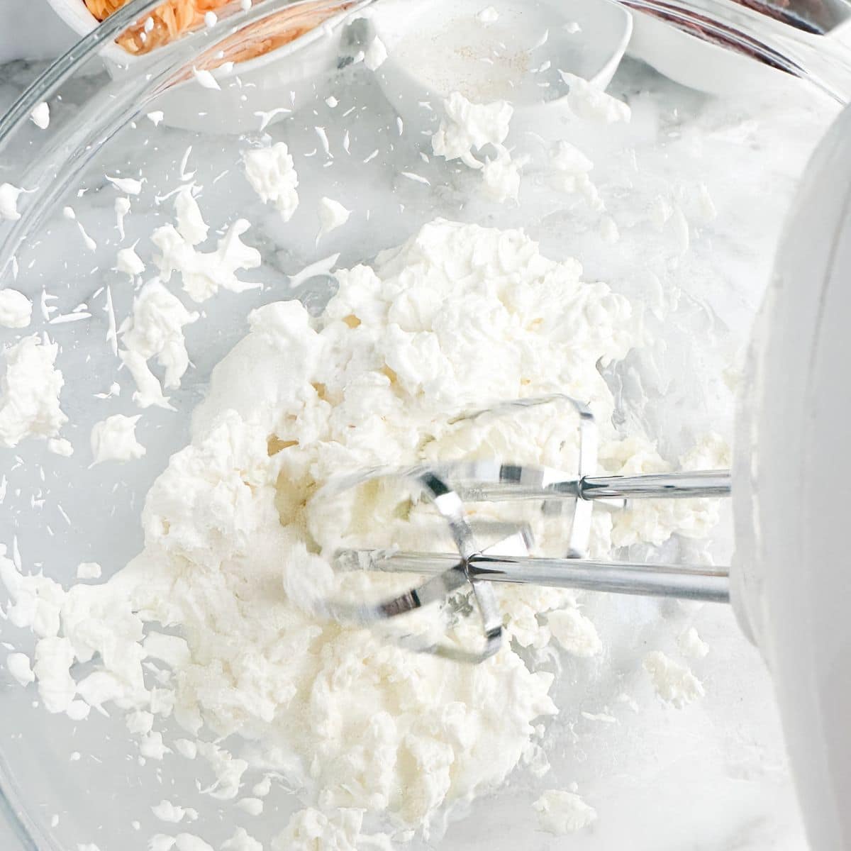 Bowl of cream cheese and sour cream with a mixer. 