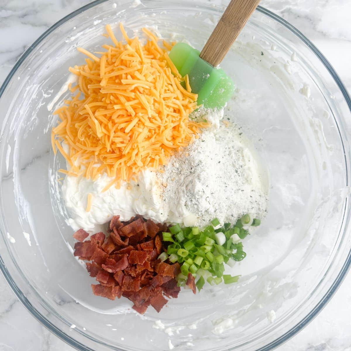 Bowl of cream cheese, shredded cheese, bacon bits, and chopped green onion. 