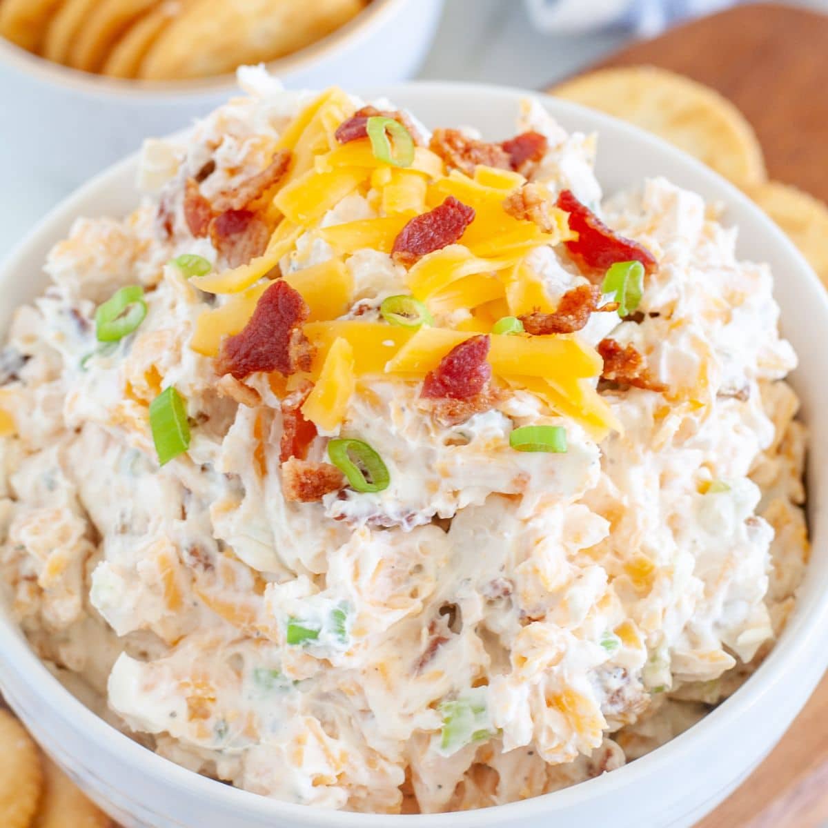 Bowl of cream cheese dip with cheese and bacon bits. 