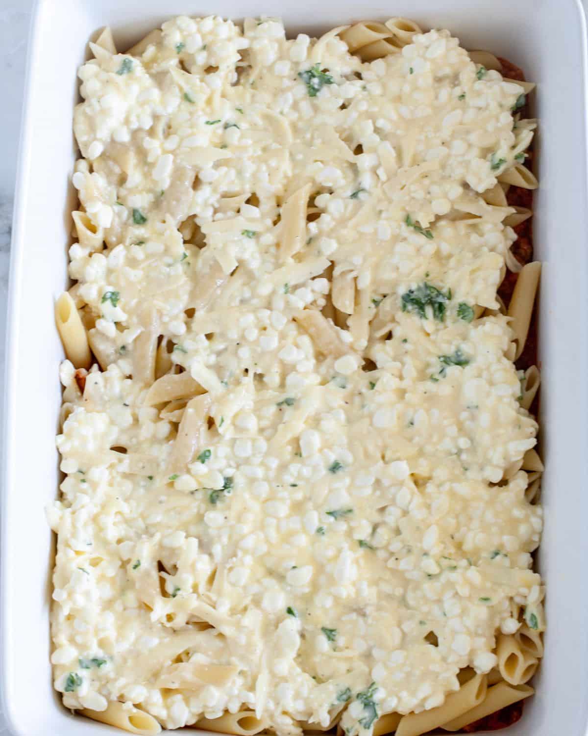 Pasta with marinara sauce and cottage cheese in a baking dish.