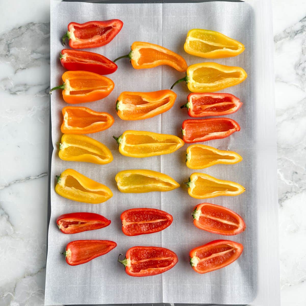 Baking sheet with mini peppers cut in half. 