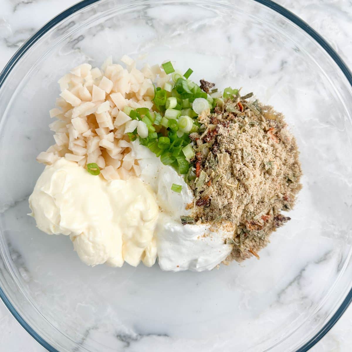 Bowl with mayonnaise, sour cream, water chestnuts, and vegetable mix. 