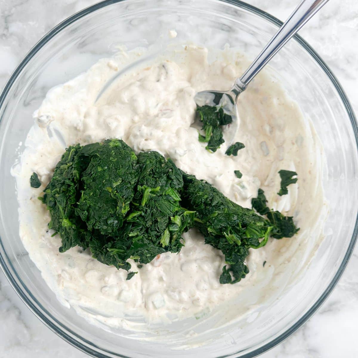 Bowl of creamy dip with frozen spinach.