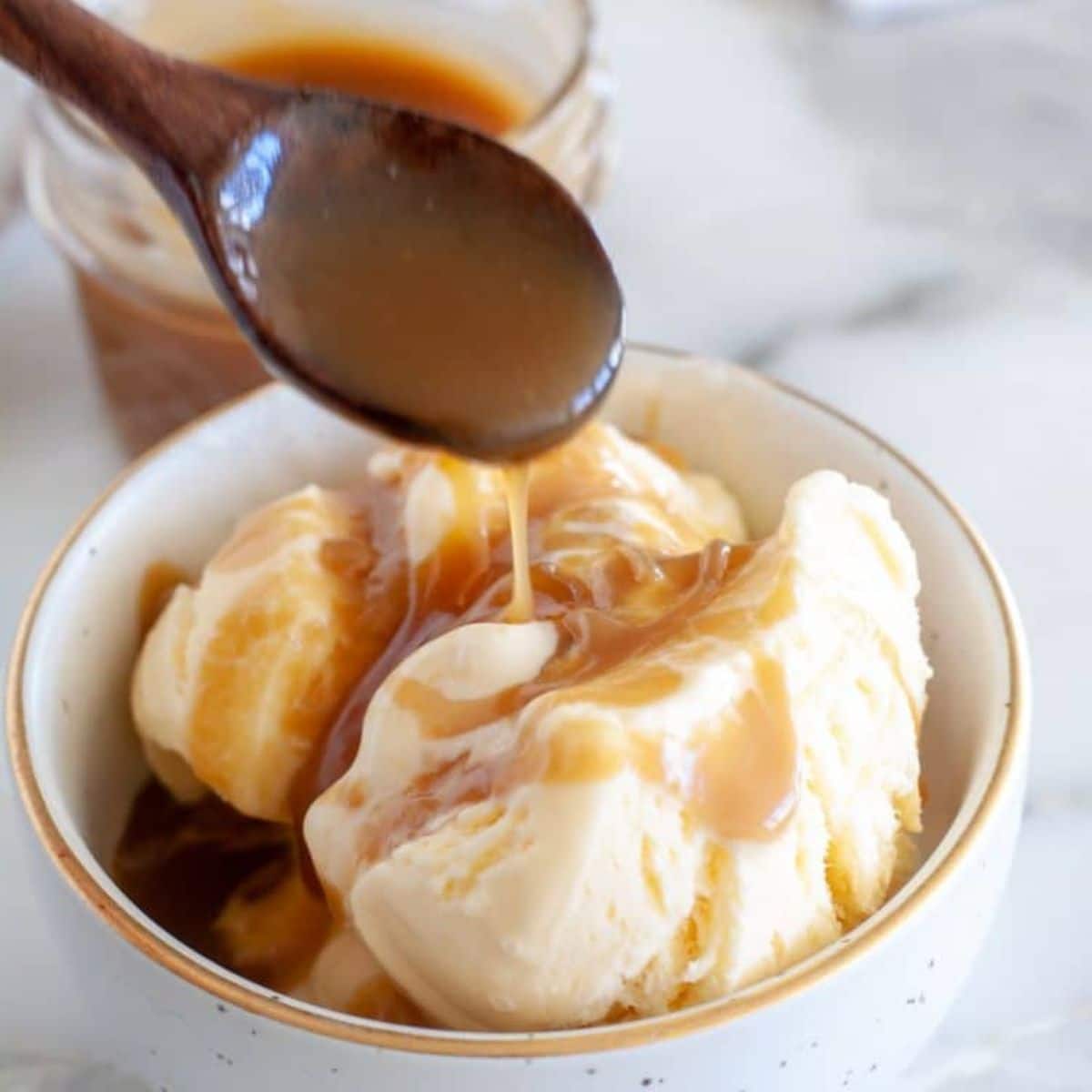 Bowl of ice cream with butterscotch sauce.