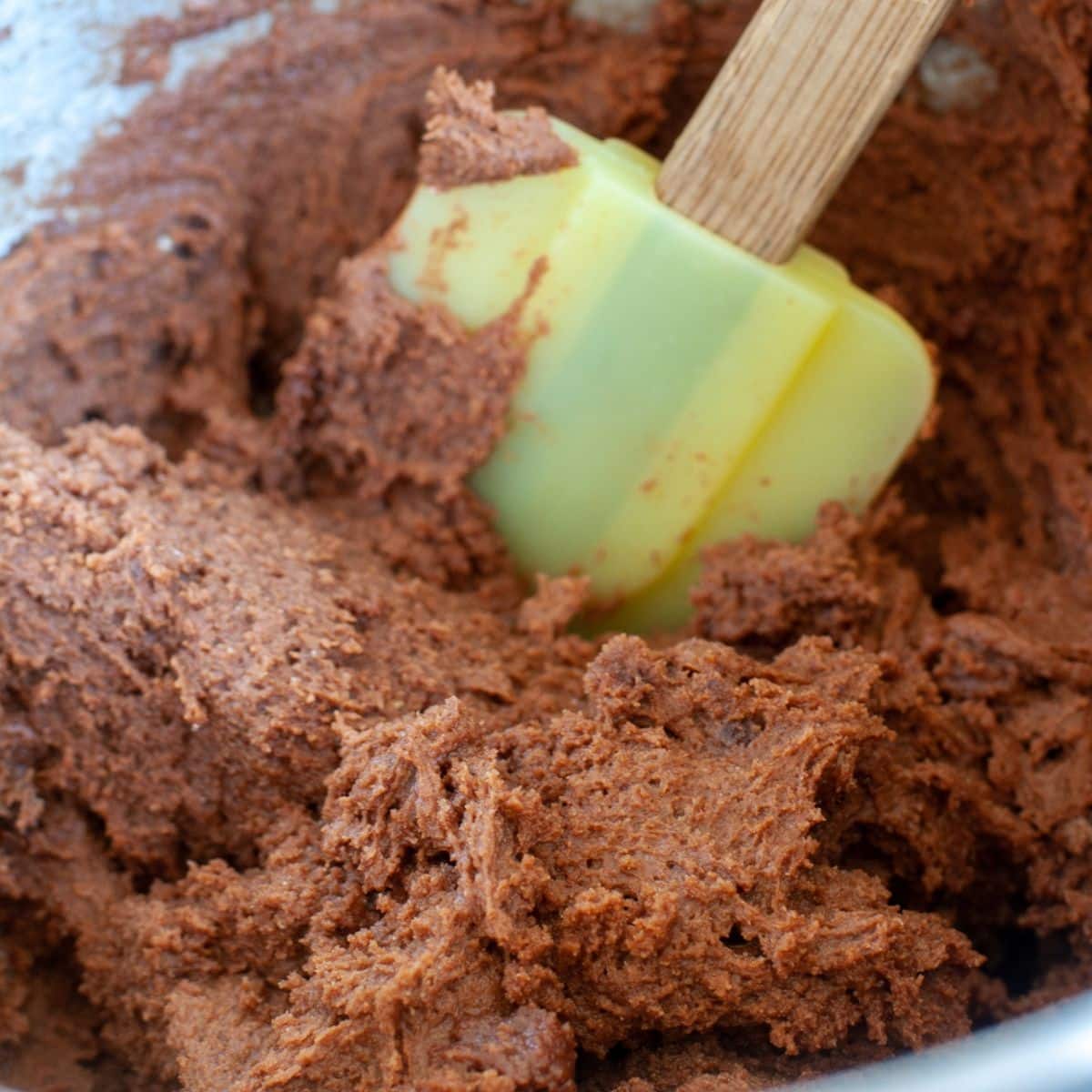 Mixing bowl with chocolate cookie dough batter and a spatula. 