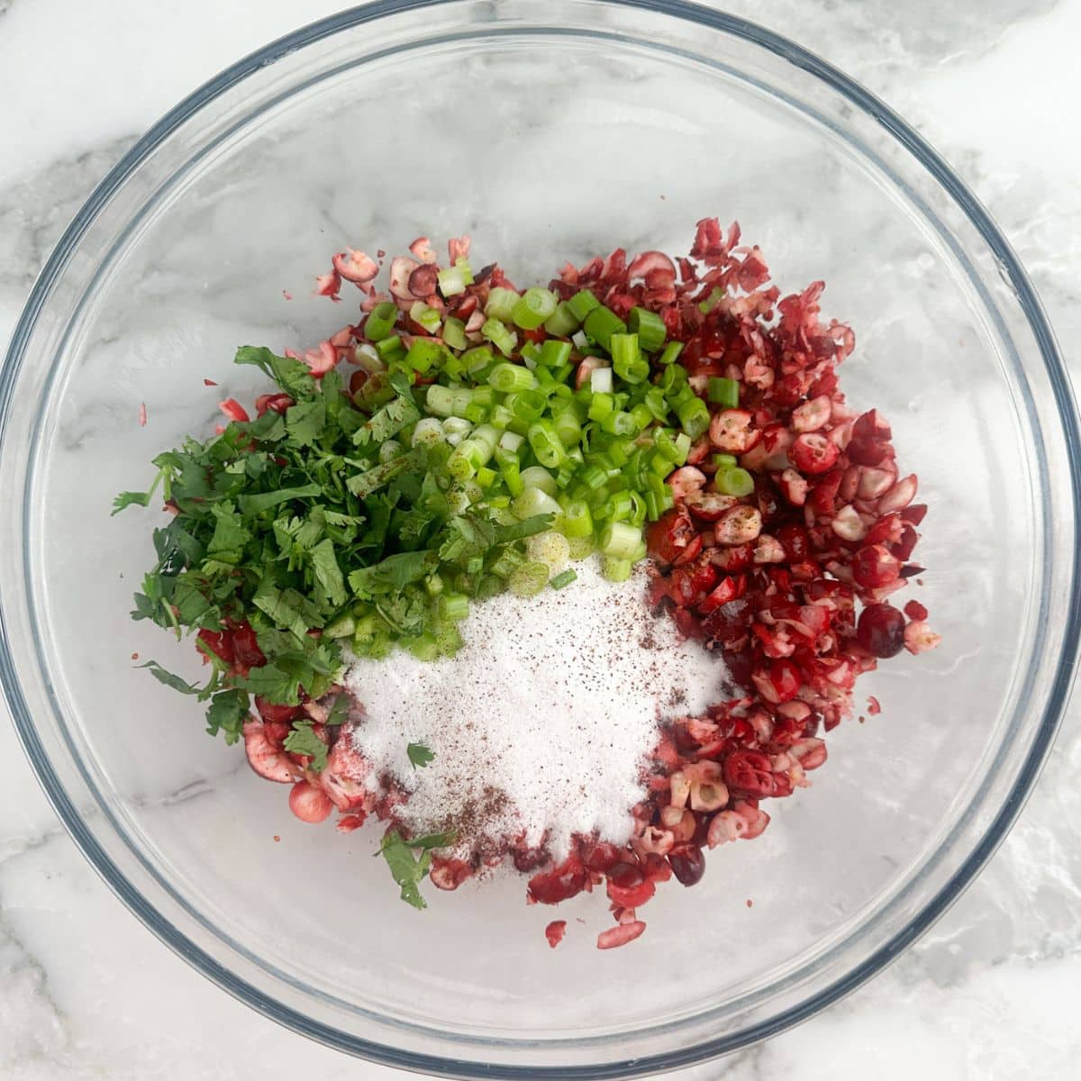 Bowl of chopped cranberries, sugar, jalapenos, and cilantro. 