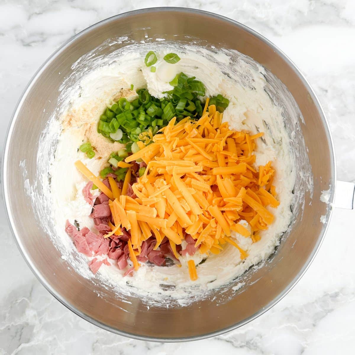 Bowl of cream cheese, shredded cheese, green onion, and chipped beef.