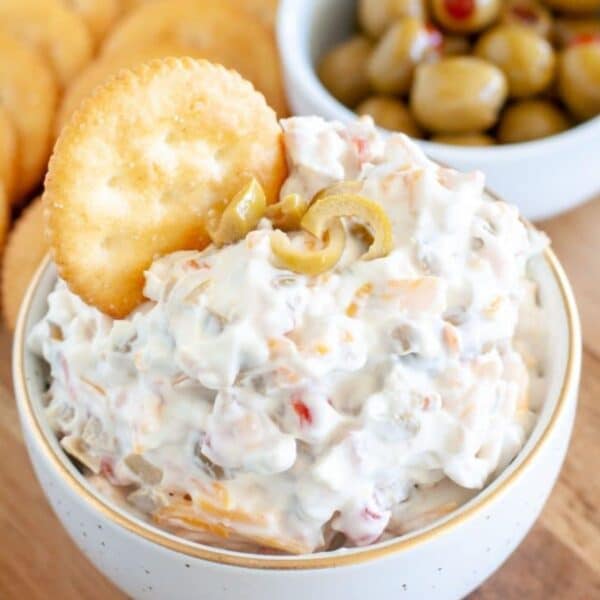 Creamy olive dip in a bowl with a Ritz cracker in the dip.