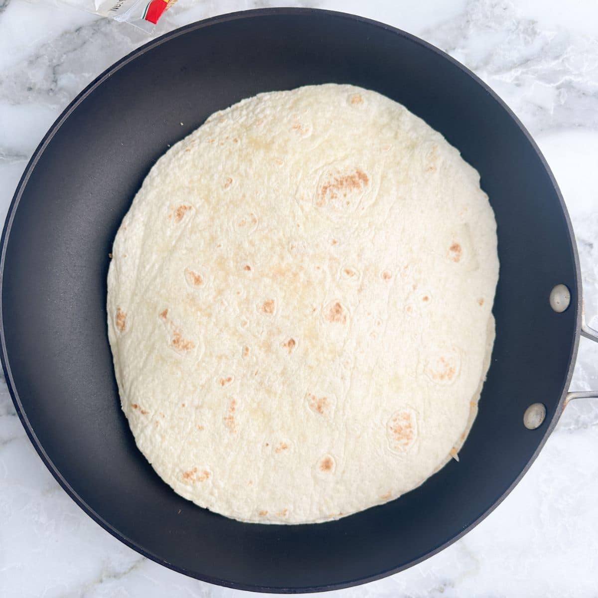 Uncooked quesadilla in a pan. 