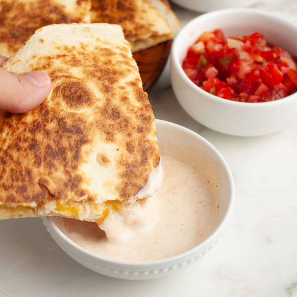 Chicken quesadilla dipping in sauce. 