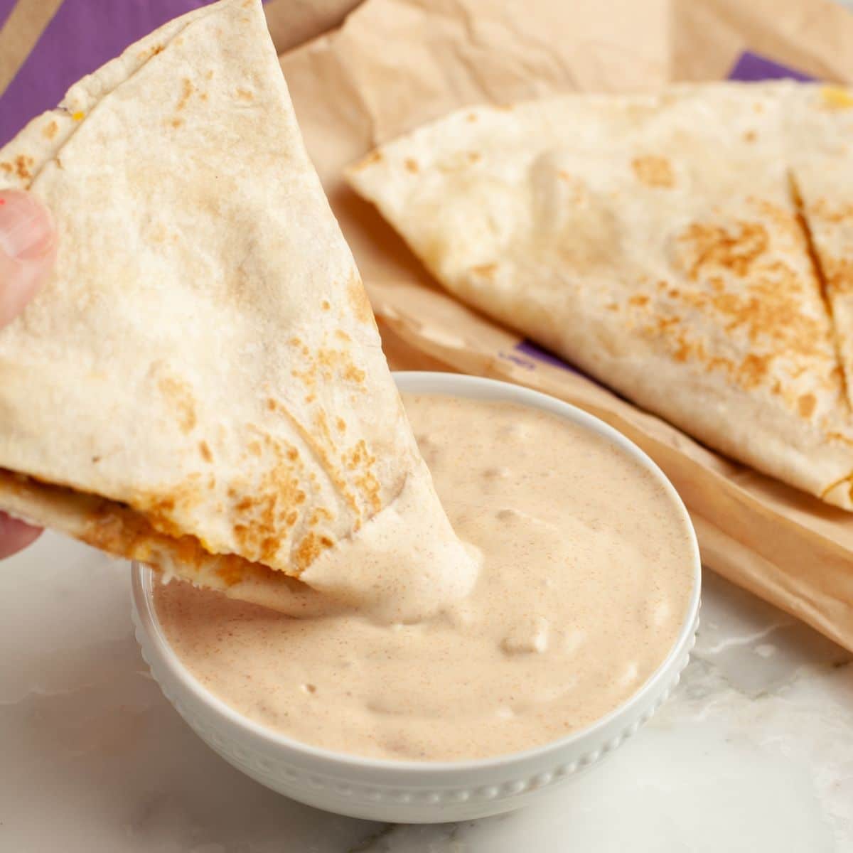 Bowl of quesadilla sauce with a quesadilla dipping into the sauce.