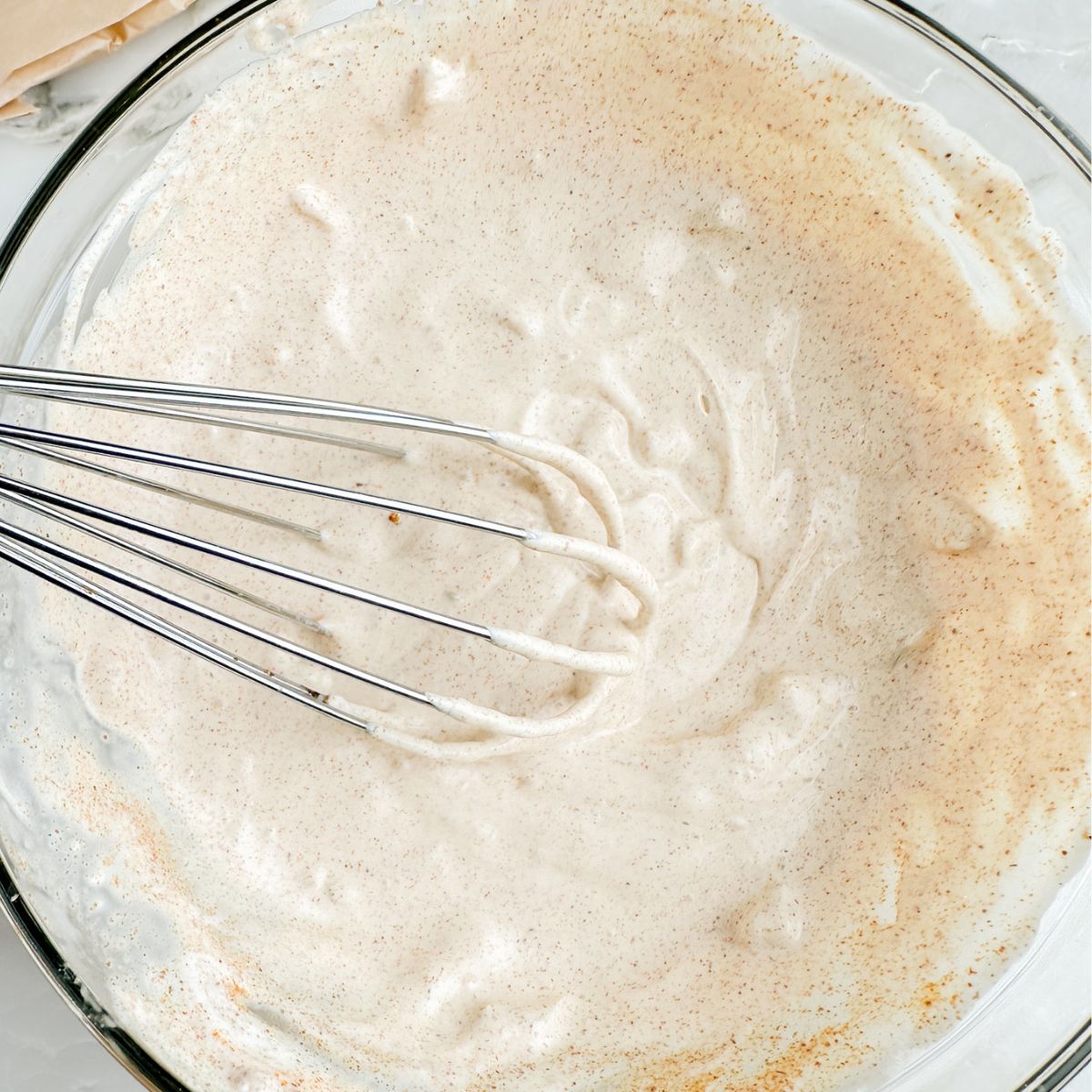 Bowl of sauce with a whisk. 