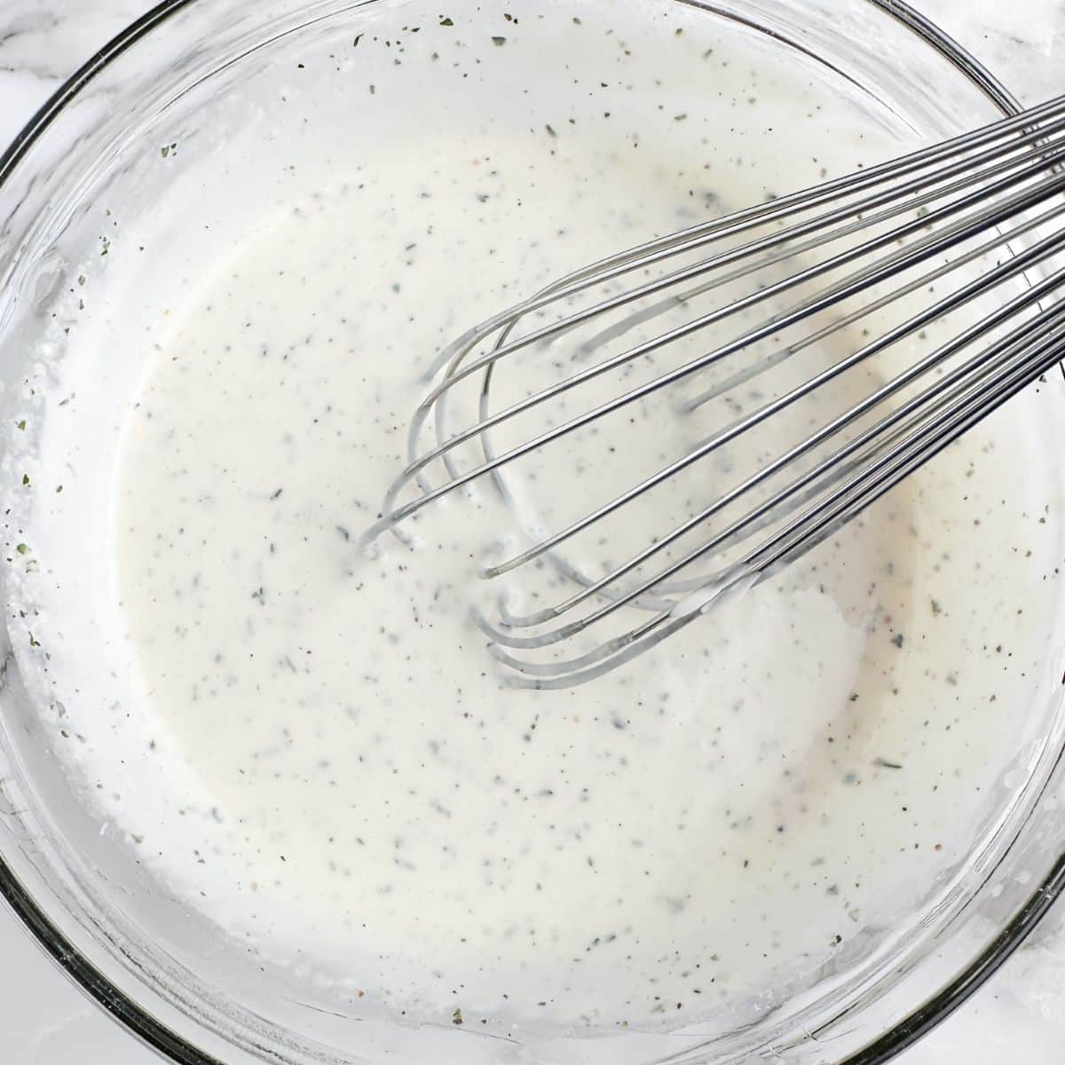 Bowl of ranch dressing with a whisk. 