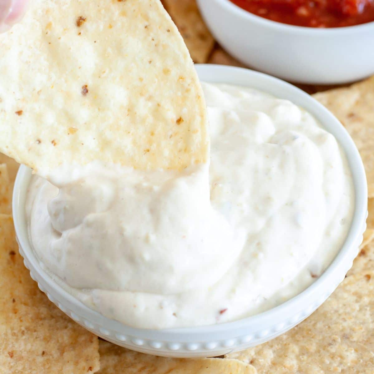 Bowl of Mexican white sauce with a tortilla chip.