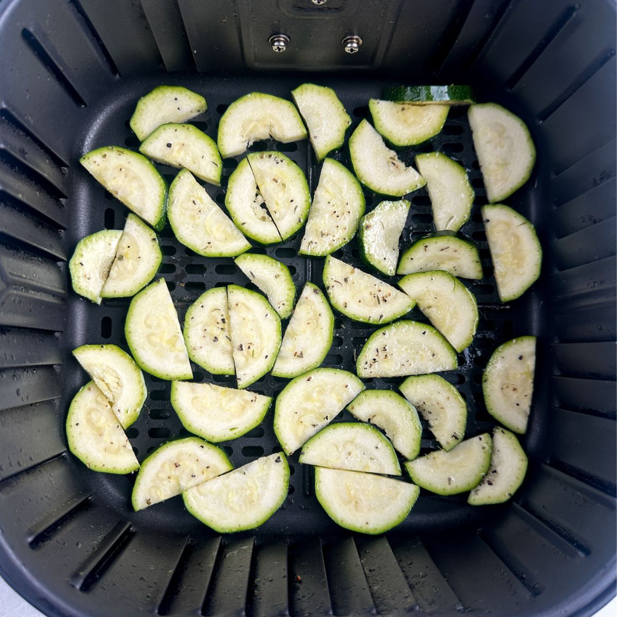 Sliced zucchini in an air fryer basket.