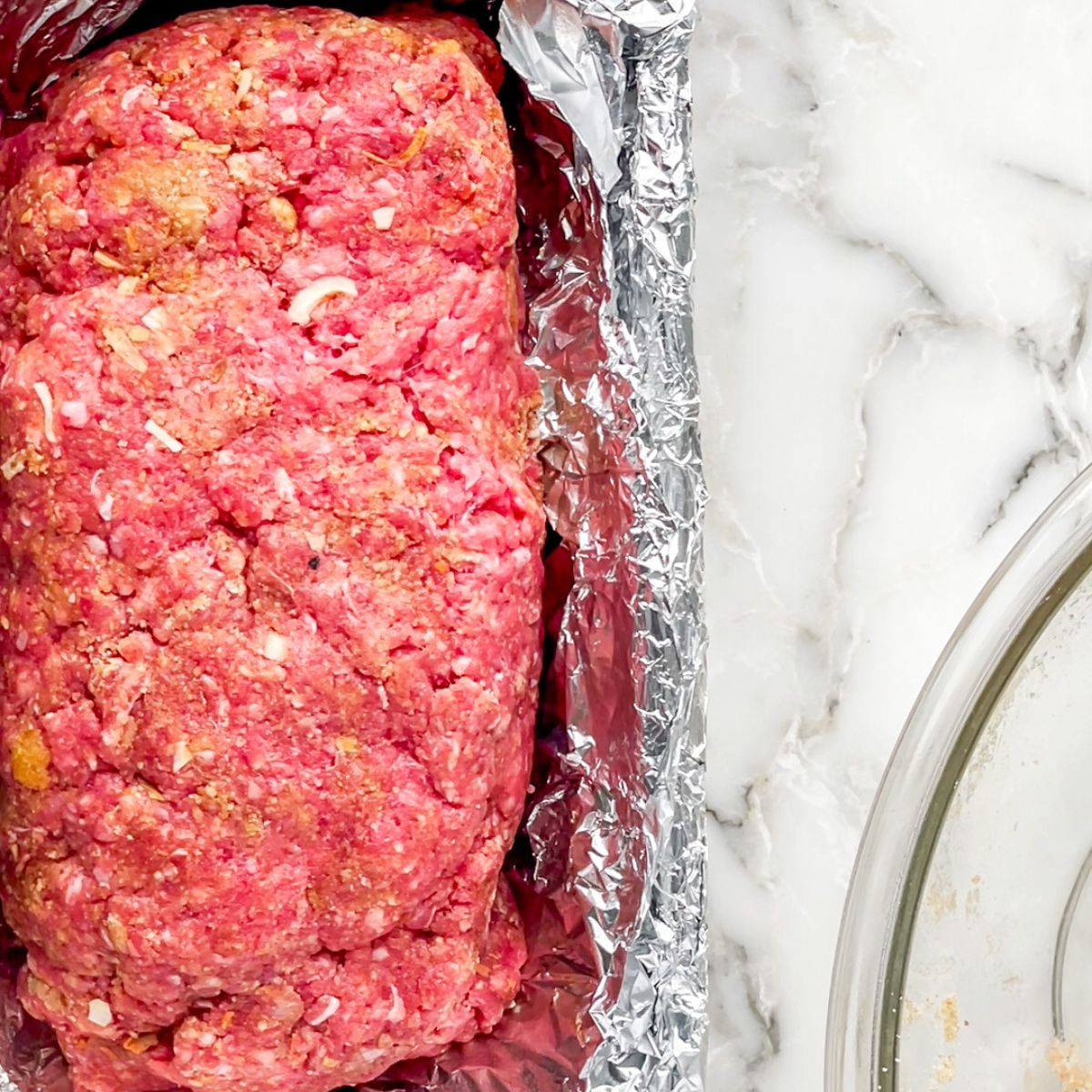 Uncooked meatloaf in a baking pan. 