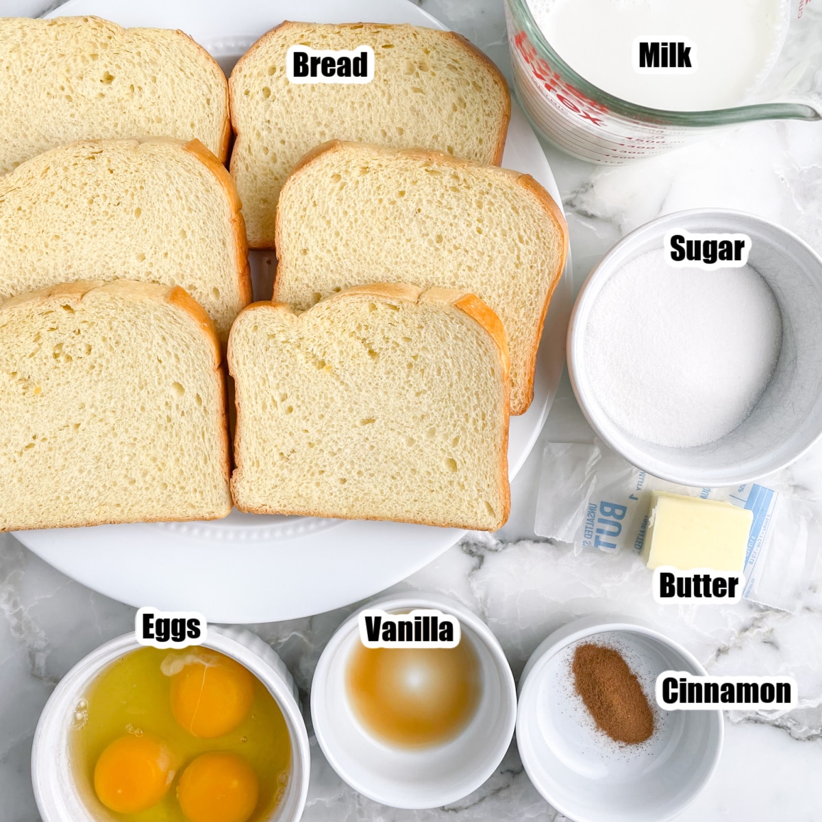 Plate of sliced bread, eggs, vanilla, milk, sugar, cinnamon, and butter. 